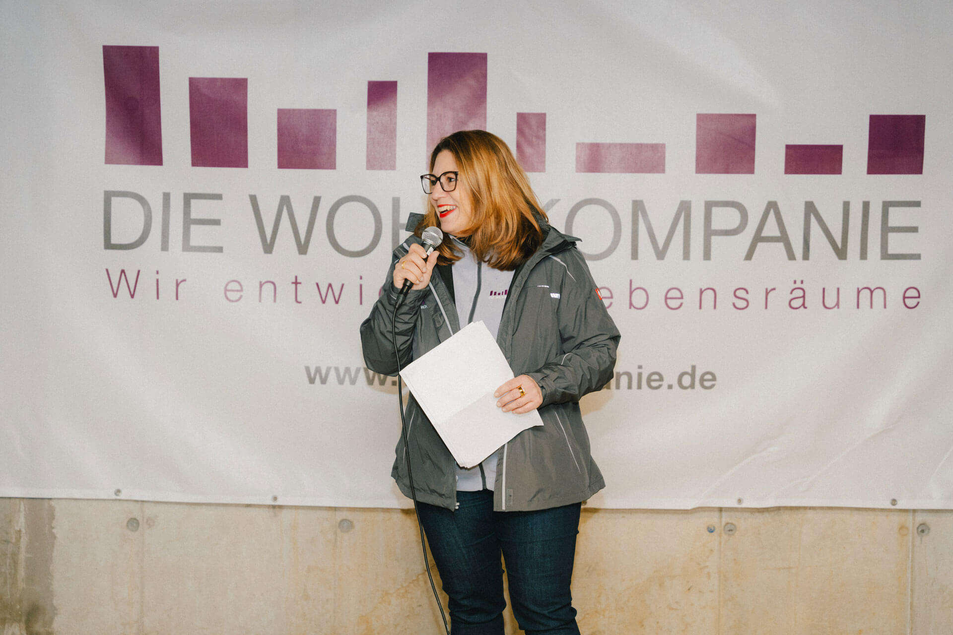 Richtfest in der Neuen Meile – Nicole Müller bei einer Rede vor dem Logo von Die Wohnkompanie