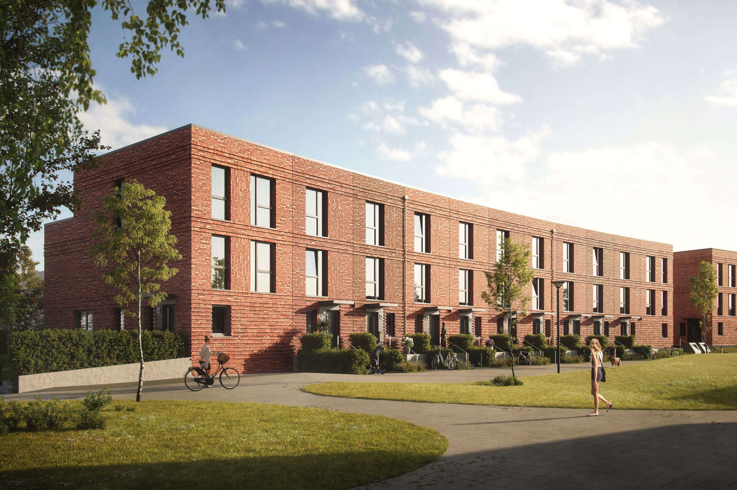 Ansicht der Fassade mit den Eingängen der Townhouses. Davor ist der Park, auf dem Weg eine Frau, die zu den Townhouses geht.