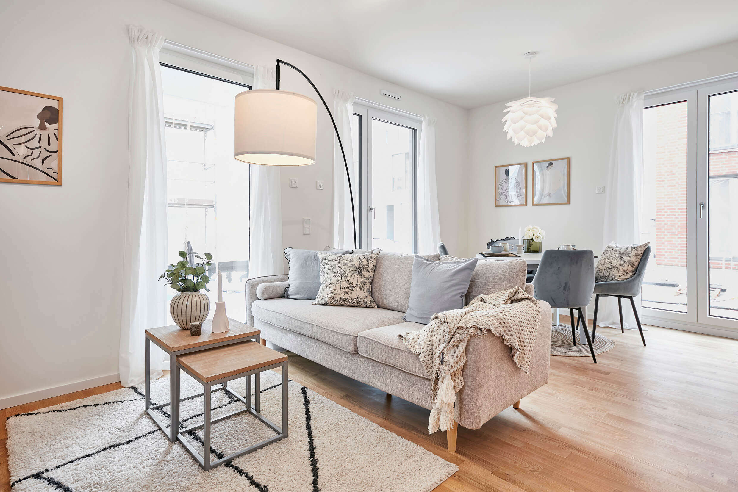 Wohnzimmer der Musterwohnung zur Miete in der Neuen Meile, Parkettboden, Blick auf das Sofa und den Esstisch im Hintergrund.